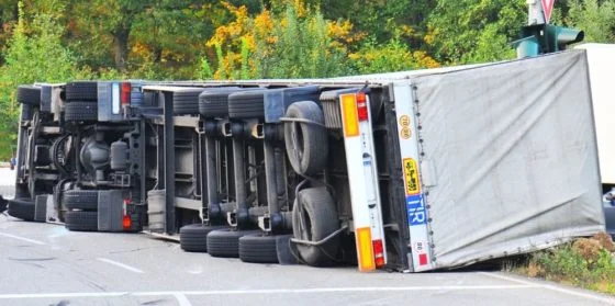 An overturned semi-truck and trailer blocking a road after a crash